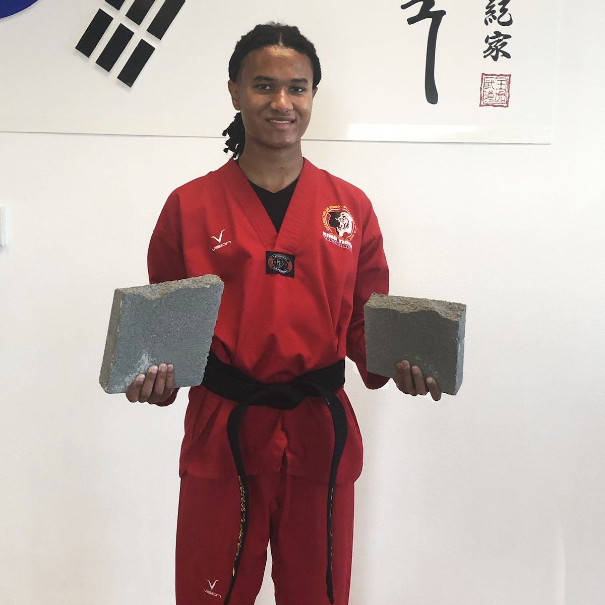 Isaiah posing in a Taekwondo uniform with a broken brick